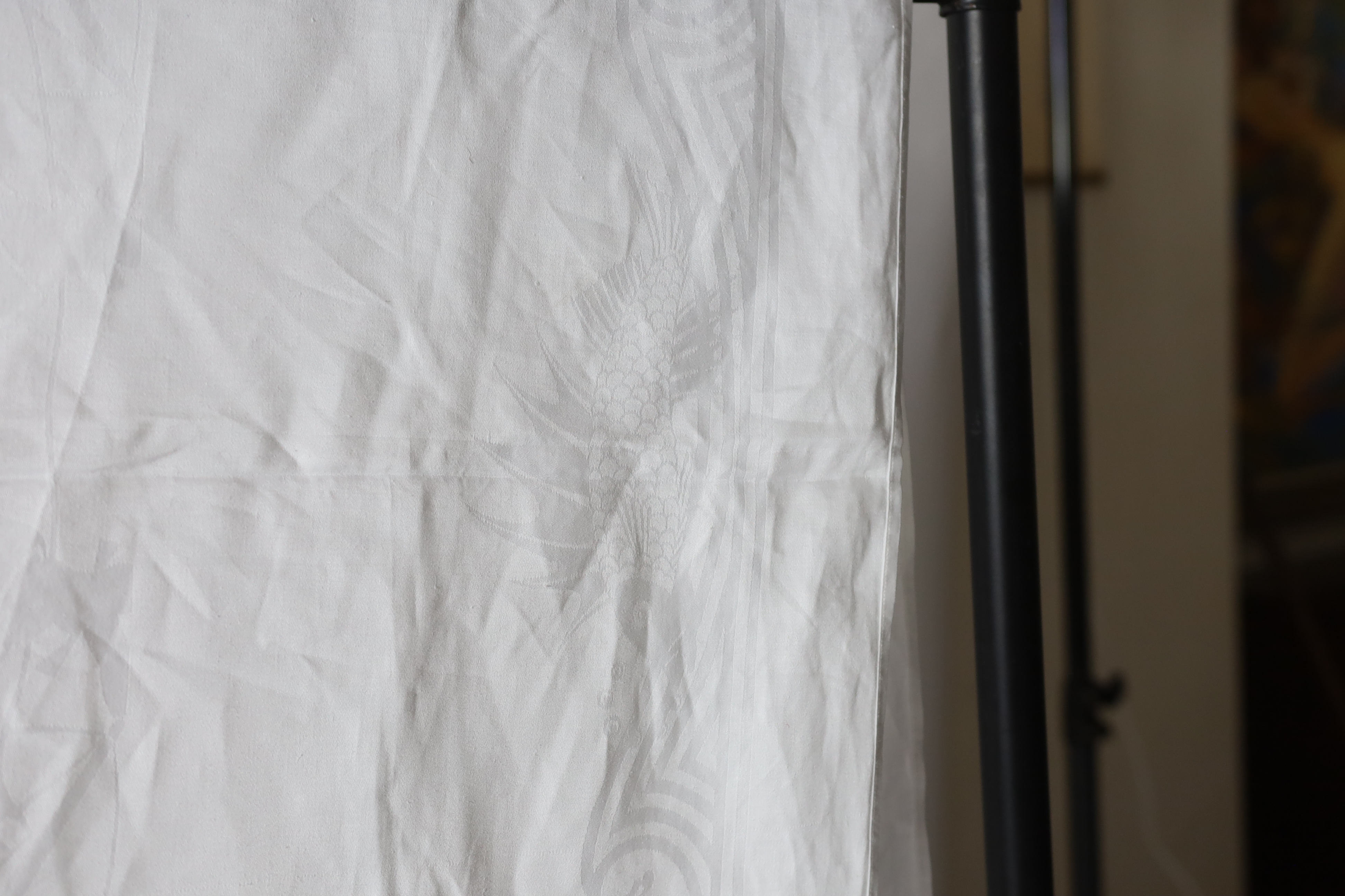 An early 20th century white linen damask table cloth, the design partly inspired by William de Morgan with galleons and fin backed fish in swirling water and tall figures with scrolls, possibly a reference to the Pilgrim